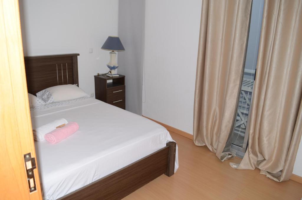 a bedroom with a bed and a lamp and a window at Apartamento Terra Branca in Praia