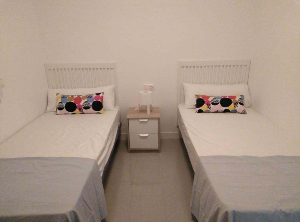 2 łóżka pojedyncze w pokoju z szafką nocną w obiekcie D3N TORREdelMAR w mieście Torre del Mar