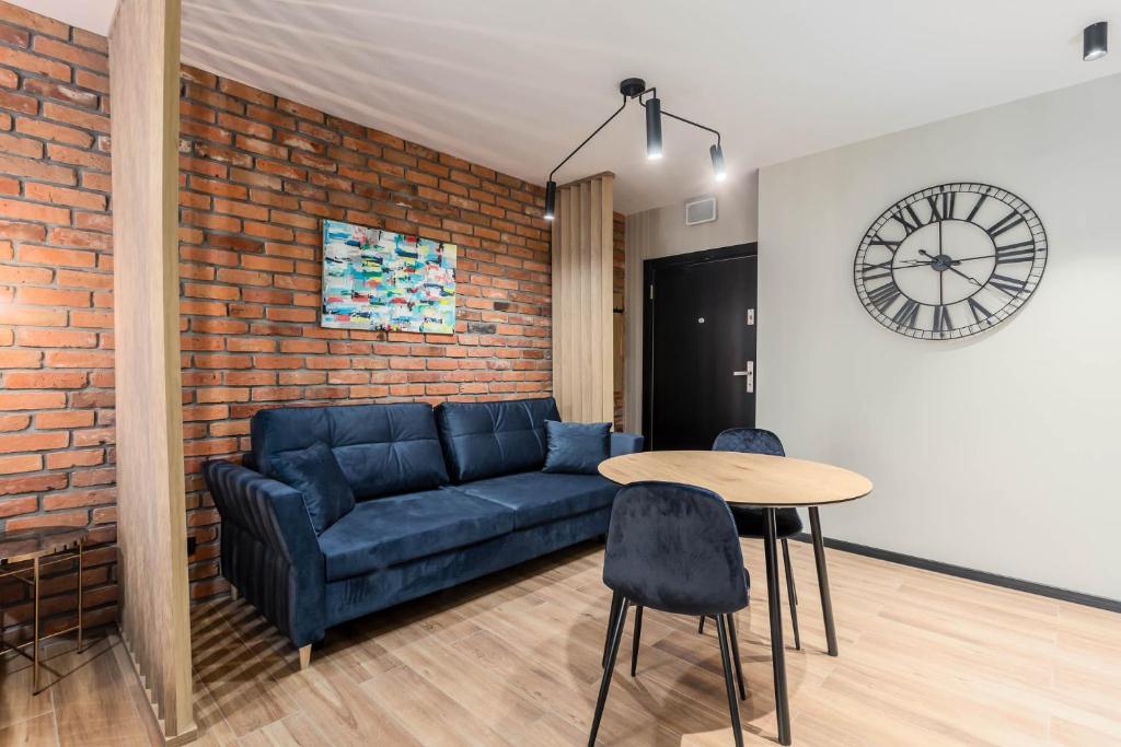 a living room with a couch and a table and a clock at Rent like home - Dwie Motławy in Gdańsk