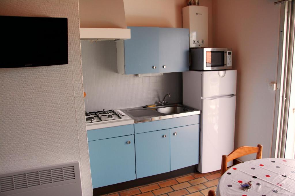 a small kitchen with blue cabinets and a white refrigerator at Studio avec vue sur la mer et balcon amenage a Le Barcares in Le Barcarès