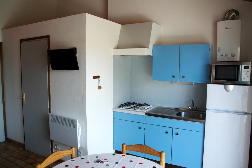 a small kitchen with blue cabinets and a table at Studio avec vue sur la mer et balcon amenage a Le Barcares in Le Barcarès