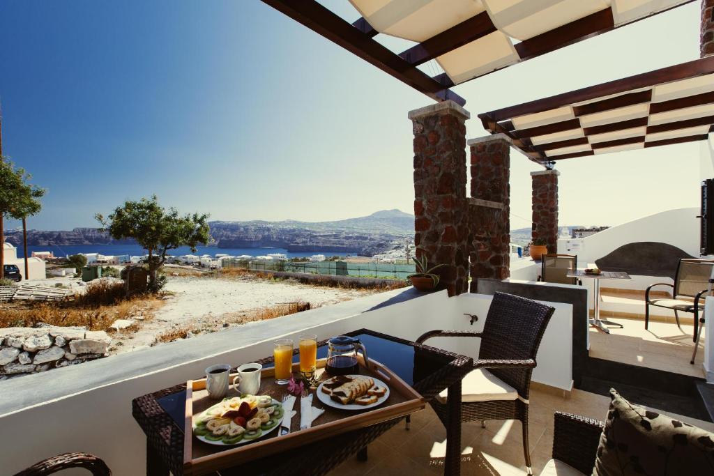 a table and chairs on a balcony with a view at Aelia Suites in Akrotiri