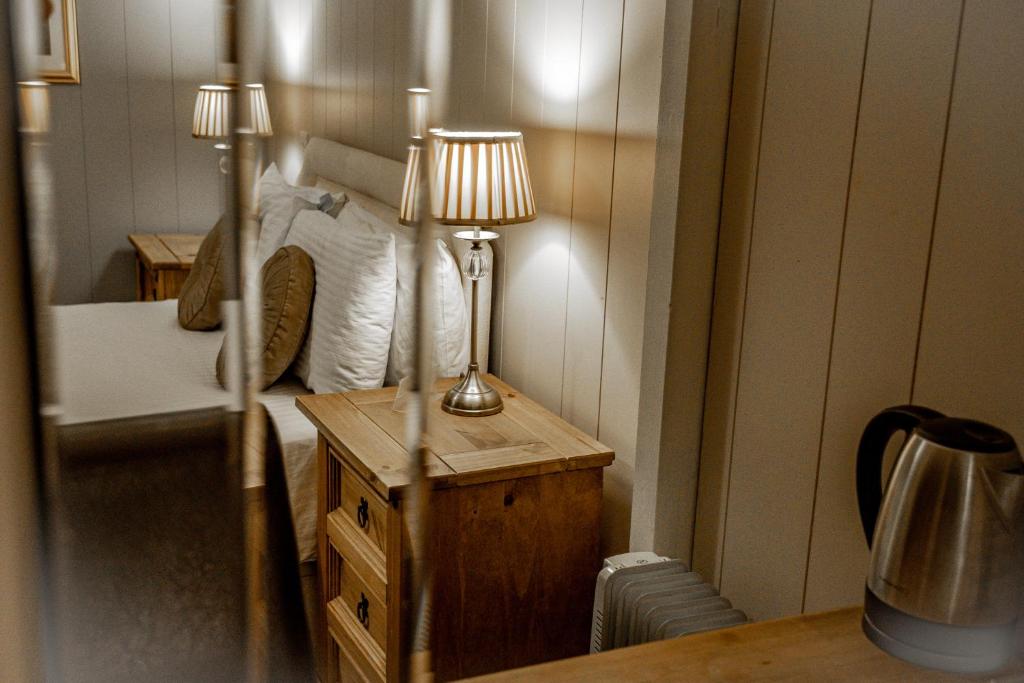 a bedroom with a bed and a table with a lamp at No1 Hotel in Wooler