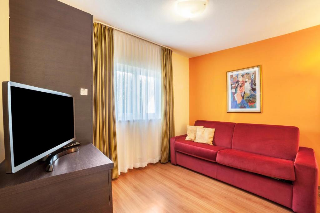 sala de estar con sofá rojo y TV de pantalla plana en Camping Adler Bungalow 18, en Naturno