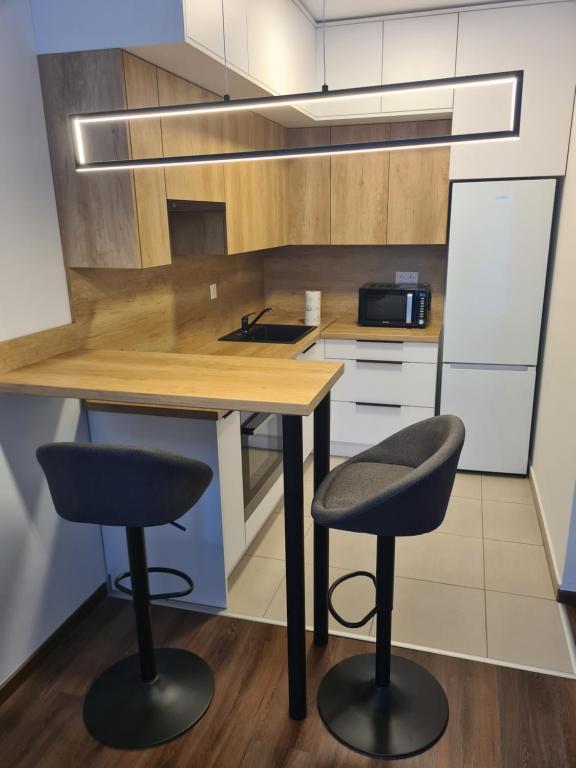 a kitchen with two bar stools and a wooden table at Aphrodité apartman in Budapest