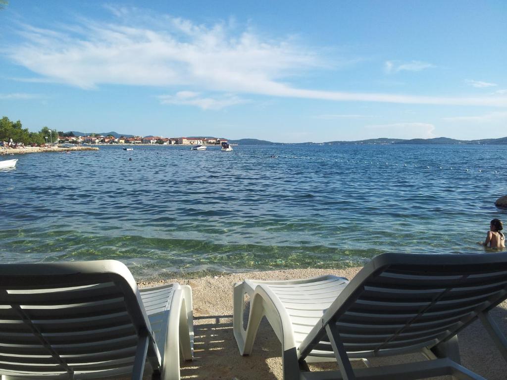 due sedie a sdraio sulla spiaggia vicino all'acqua di Apartments Lorena a Zara (Zadar)