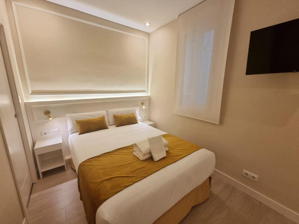 a bedroom with a large bed with a television on the wall at CH Velarde in Madrid