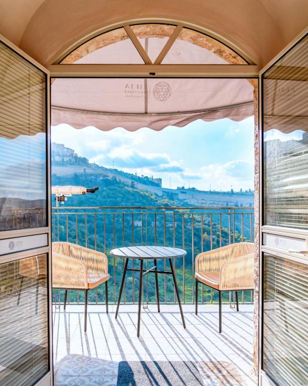 a room with a table and chairs on a balcony at Lifta Boutique Hotel & Spa in Jerusalem