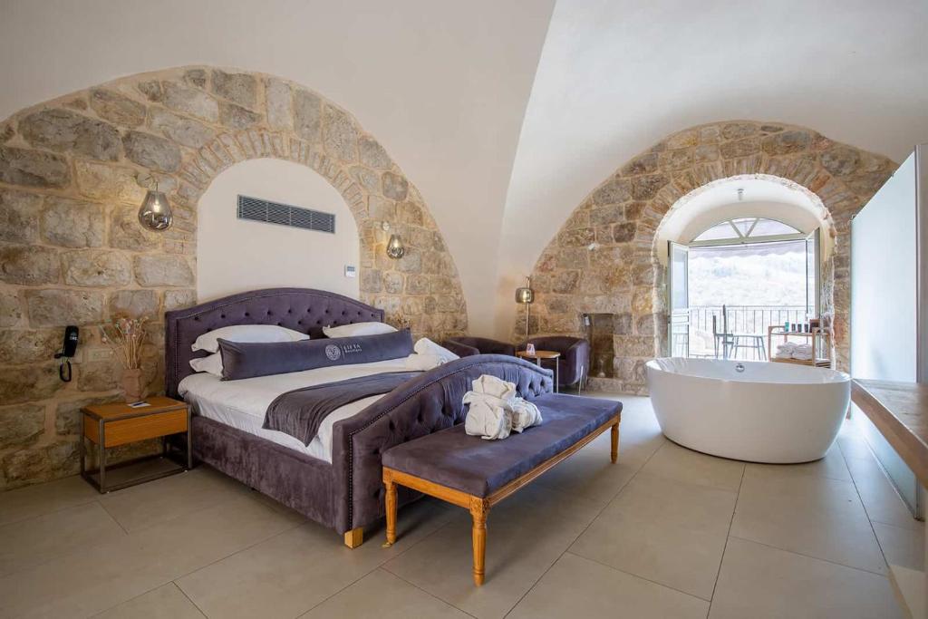 a bedroom with a bed and a tub in a room at Lifta Boutique Hotel & Spa in Jerusalem