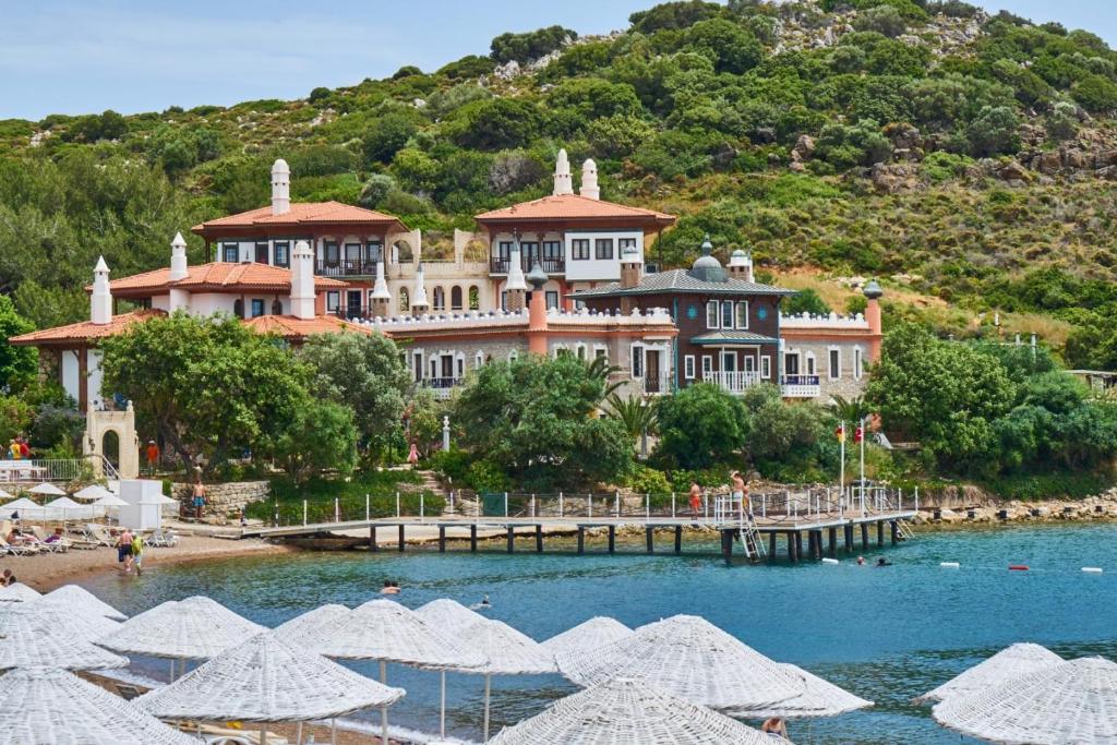 a large building on a hill with a body of water at Marble Arch Hotel By Perili Datça in Datca