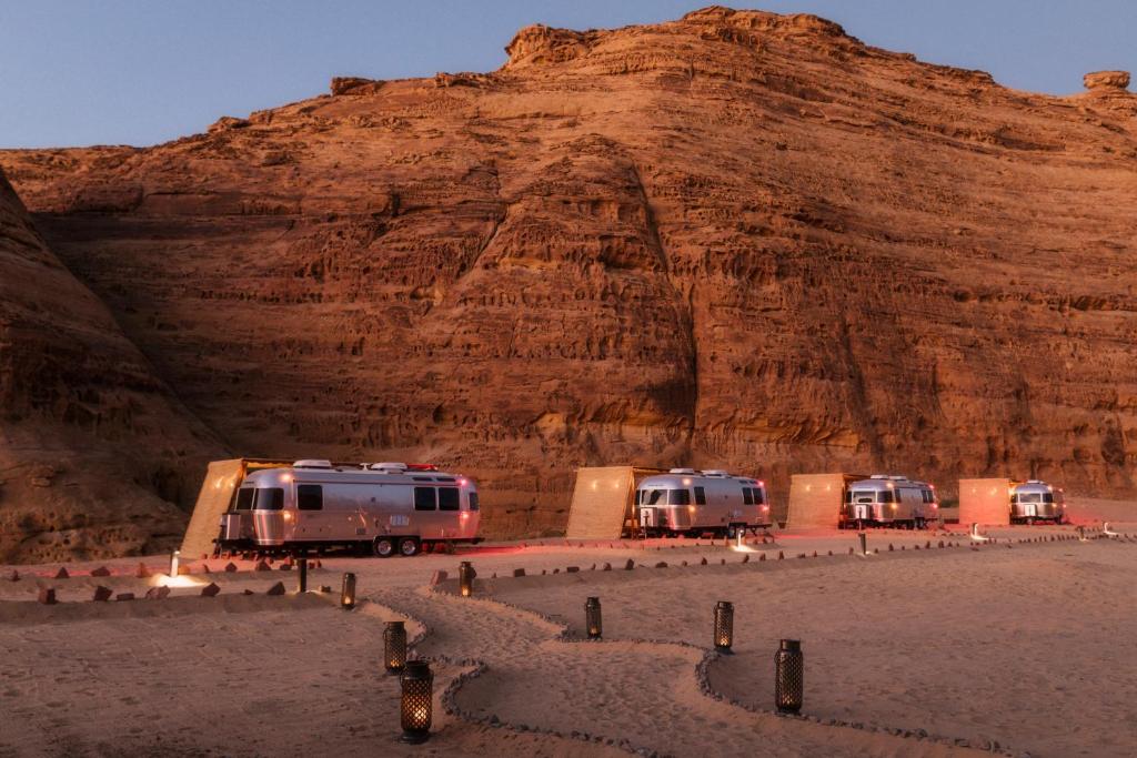 três autocaravanas estacionadas em frente a uma montanha em Caravan by Habitas AlUla em Al-ʿUla