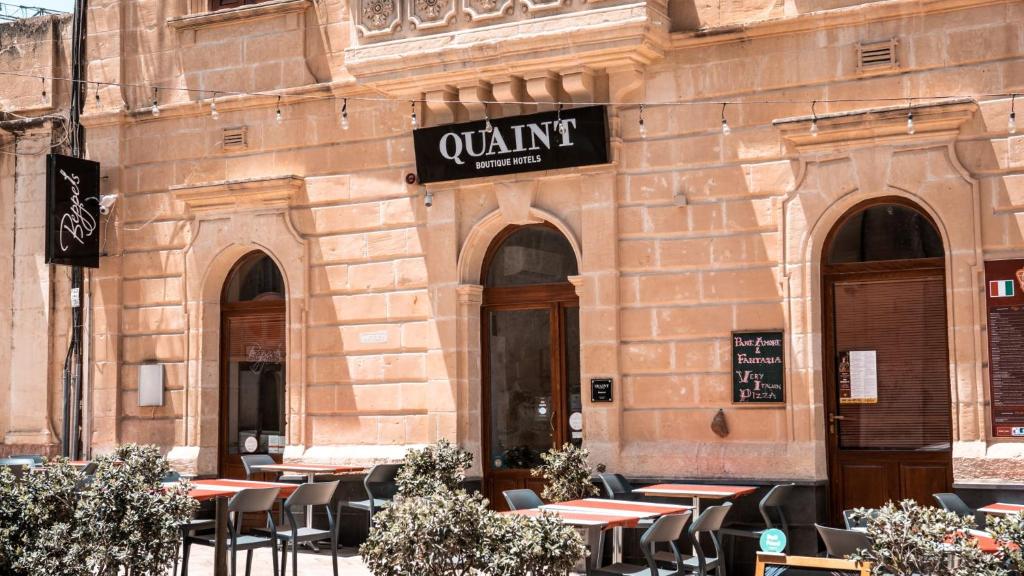 Quaint Boutique Hotel Sannat في سانّات: مطعم فيه طاولات وكراسي امام مبنى