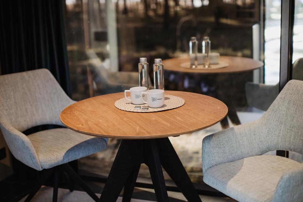 een houten tafel met twee stoelen, flessen en bekers bij ÖÖD Hötels Laheranna SÄRA -with sauna in Punakivi