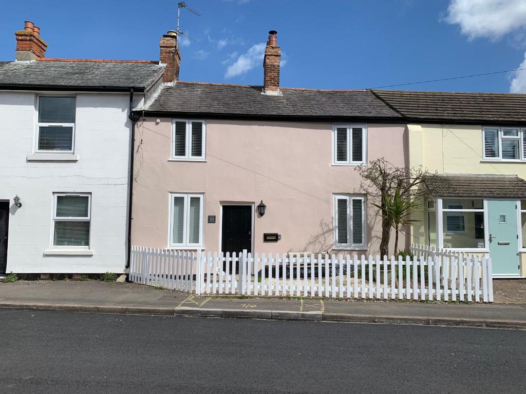 a white and pink house with a white fence at Smugglers Cottage in Christchurch