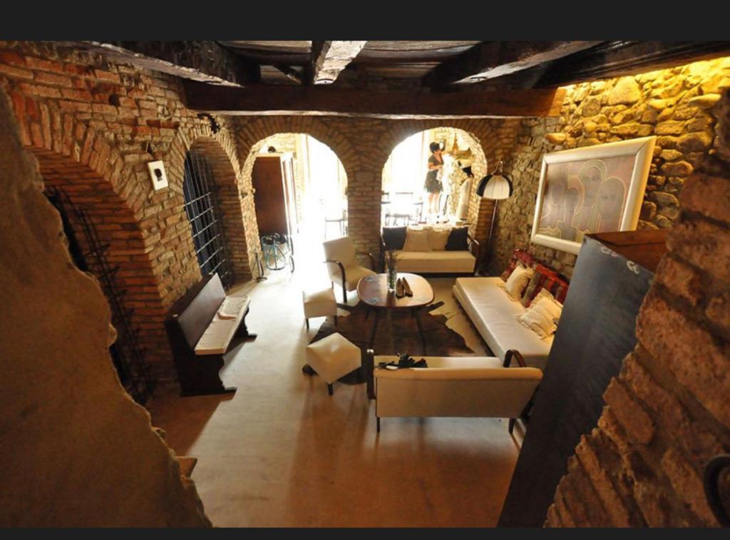 uma sala de estar com sofás e cadeiras numa parede de tijolos em I CATARI ...nel cuore di Monforte d'Alba em Monforte dʼAlba