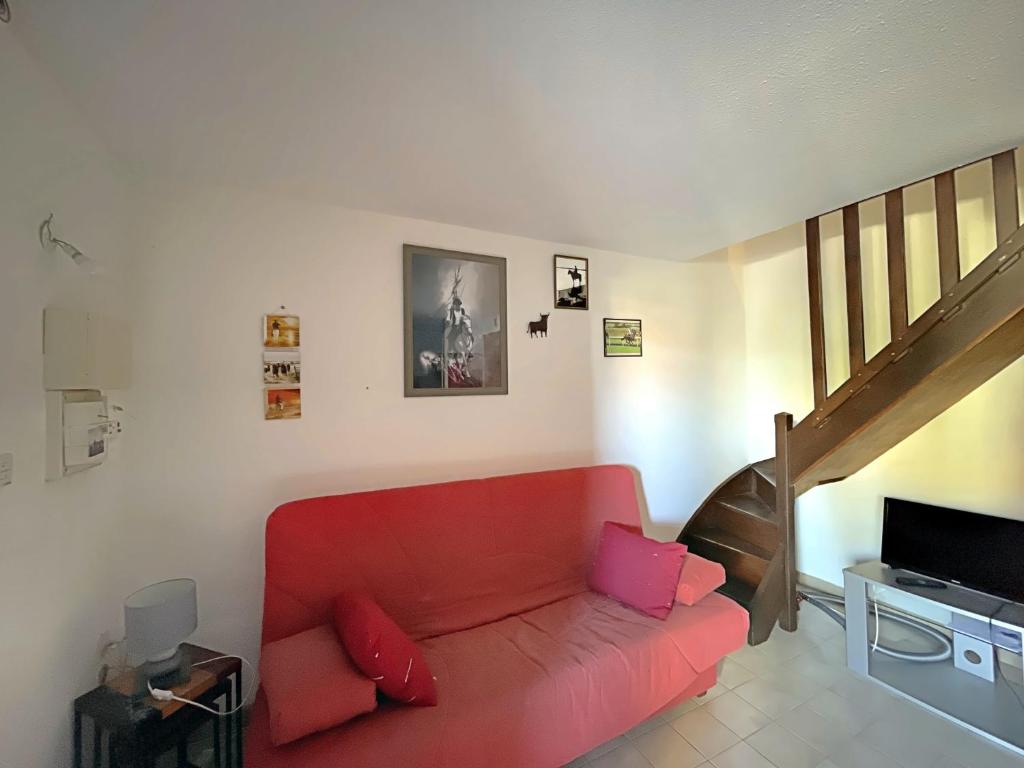 - un salon avec un canapé rouge et un escalier dans l'établissement Ref LS64: Maison 4-6 pers Les Hameaux de Camargue, à Saintes-Maries-de-la-Mer