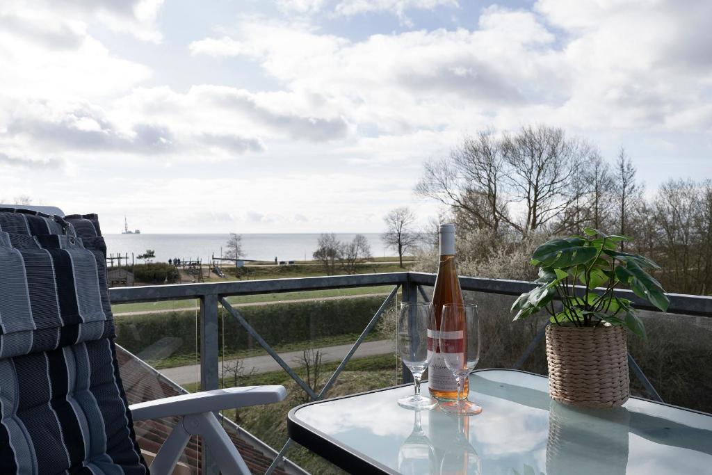 einen Glastisch mit einer Flasche Wein und eine Pflanze auf dem Balkon in der Unterkunft Ferienwohnung Seeigel mit Balkon im Kaiserhof 5 in Kellenhusen