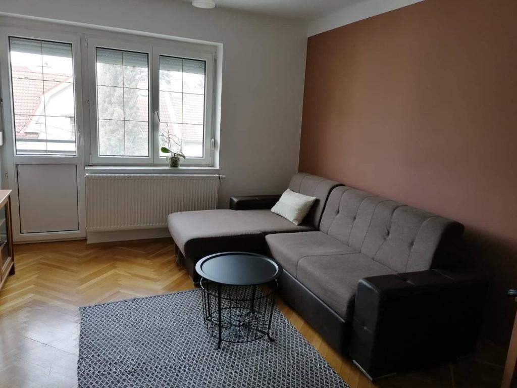 uma sala de estar com um sofá e uma mesa em ALEX Apartman em Sopron