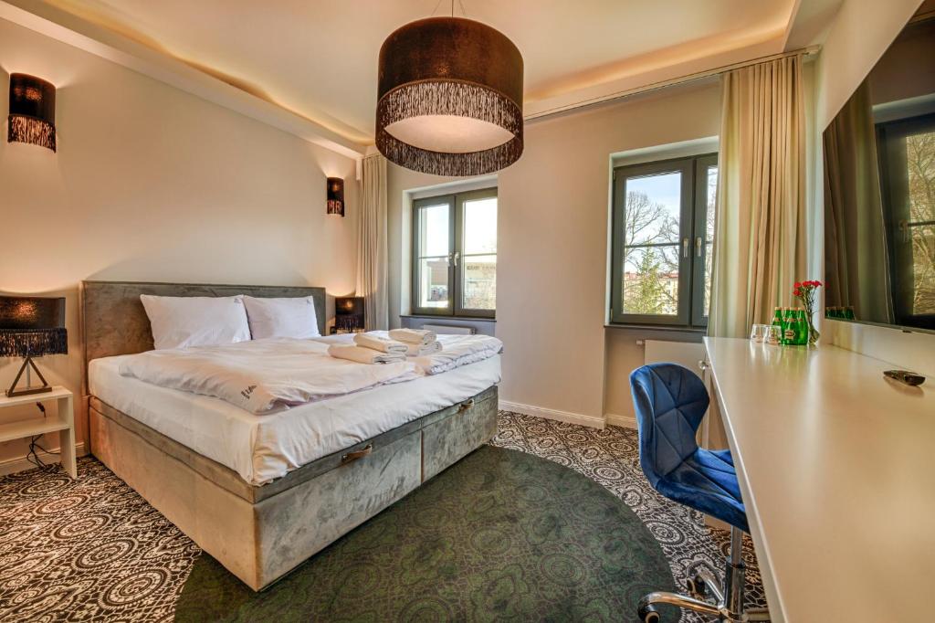 a bedroom with a bed and a desk and windows at Fregata Kołobrzeg in Kołobrzeg