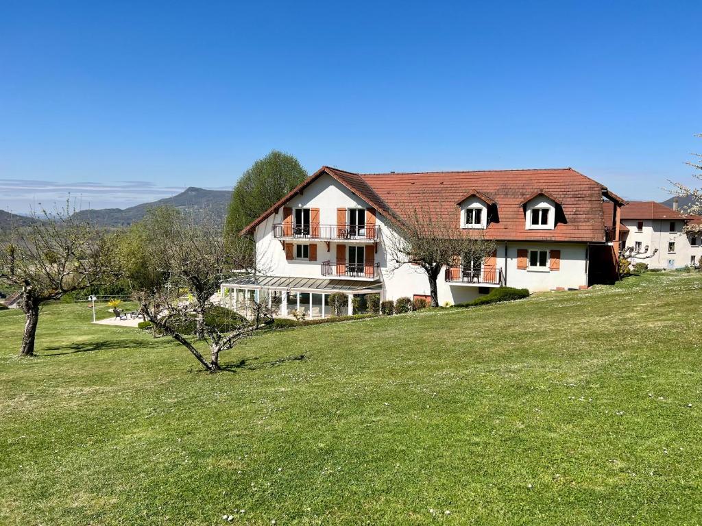 una casa grande en una colina con un campo verde en Hôtel les Bergeronnettes, en Champagneux