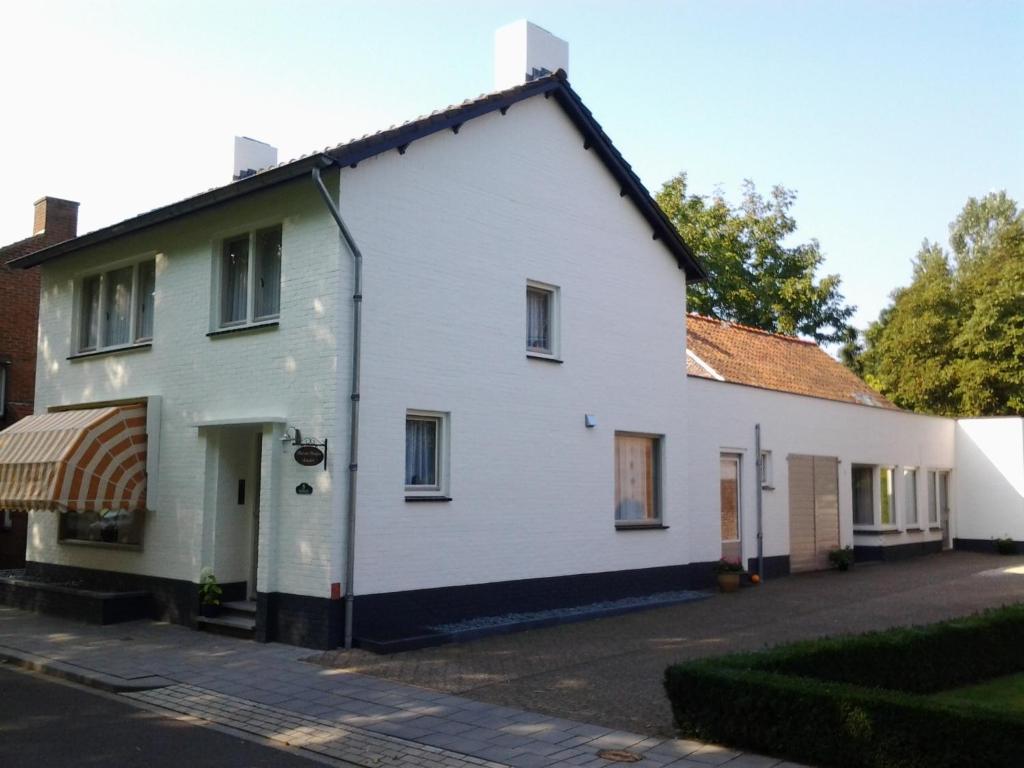 uma casa branca com um toldo numa rua em Vakantie Appartementen Engelen em Stevensweert