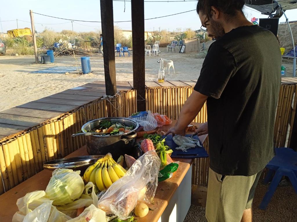 a man standing next to a table full of fruits and vegetables at BH מתחם קמפינג ואוהלים in Nevatim