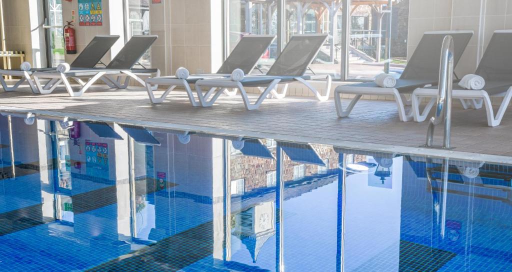 a swimming pool with lounge chairs next to the water at Last Drop Village Hotel & Spa in Bolton