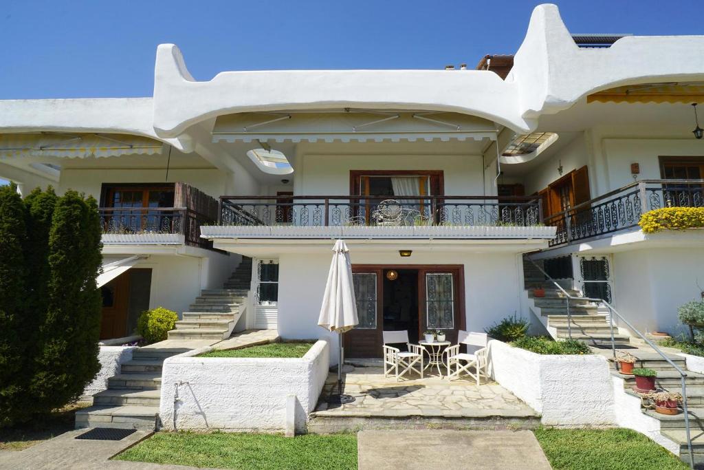 a large white house with a table and an umbrella at Villa Vasiliki in Paralía Avdhíron