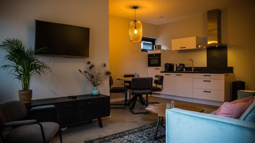 een woonkamer met een bank en een tafel en een keuken bij Appartement - Kon Emmaweg 26 Vrouwenpolder 'Uitspanning Oranjezon' in Vrouwenpolder