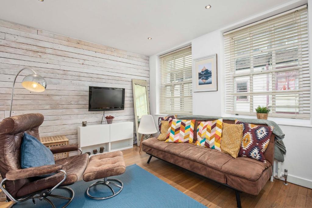 ein Wohnzimmer mit einem Sofa und einem TV in der Unterkunft Boho Apartment In The Lanes in Brighton & Hove