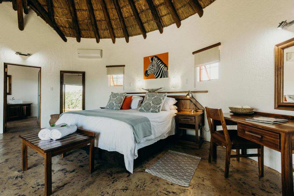 a bedroom with a bed and a desk at Mopane Bush Lodge in Linton