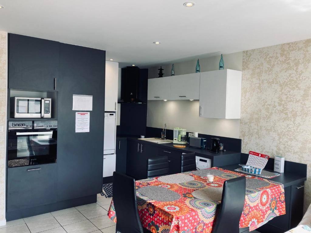 une cuisine avec une table et une cuisine avec des armoires noires dans l'établissement Standing, luminosité à 100m de la mer, T3 prestige, à Saint-Hilaire-de-Riez