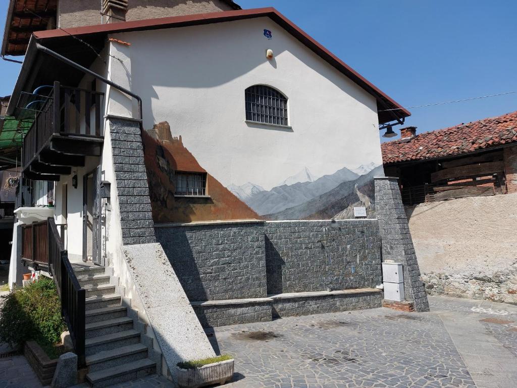 une fresque murale sur le côté d'un bâtiment avec des escaliers dans l'établissement Casa del Rustico, Indipendente vista Sacra con dipinto, à Caprie