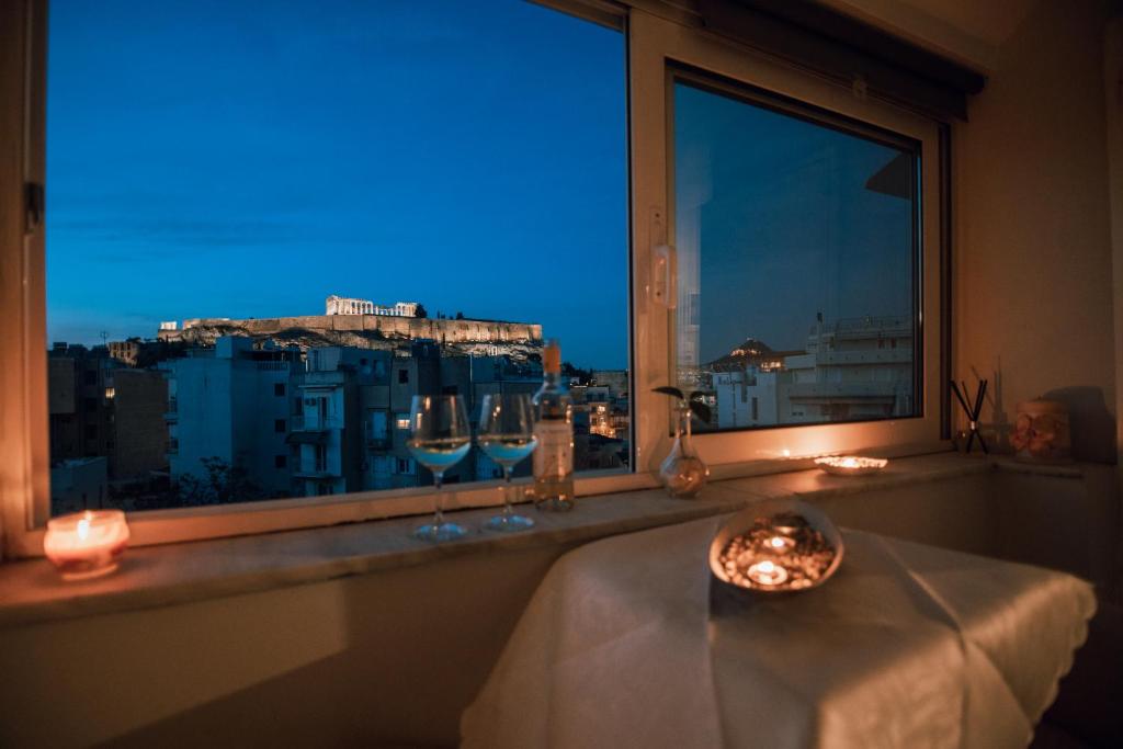 ein Fenster mit Weingläsern auf einem Tisch mit Aussicht in der Unterkunft Acropoli's balcony in Athen