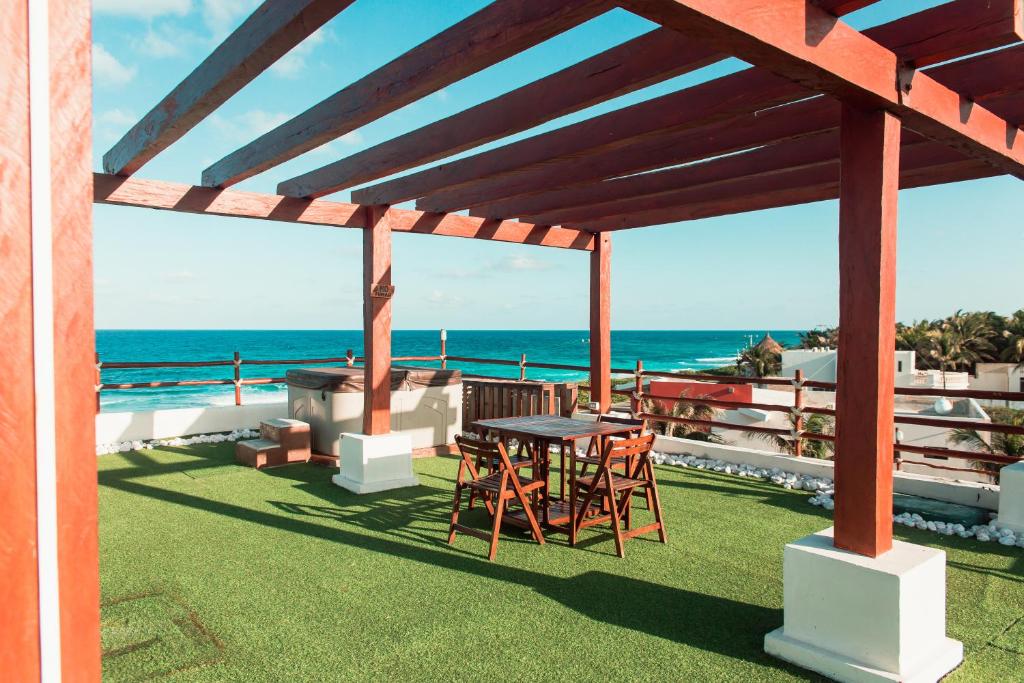 un patio con tavolo, sedie e vista sull'oceano di ISLA MUJERES MAYAKITA LUXURY VILLA with ROOFTOP JACUZZI a Isla Mujeres
