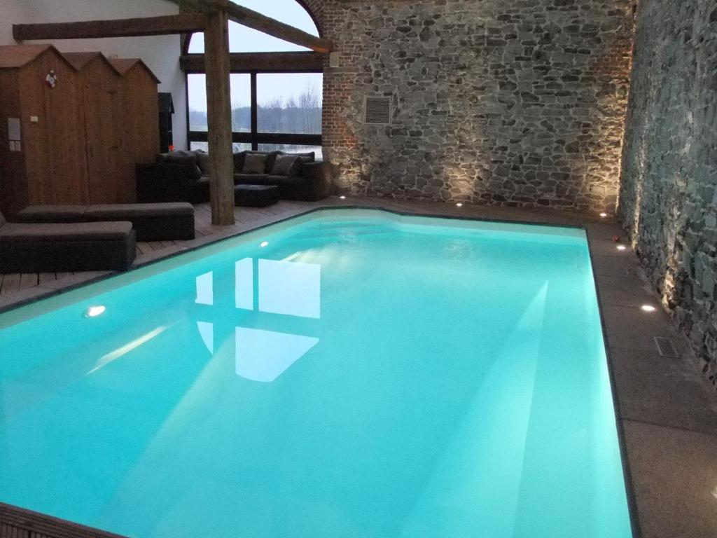 una gran piscina en una habitación con una pared de ladrillo en B&B Le Pre Sabot, en Écaussinnes-dʼEnghien