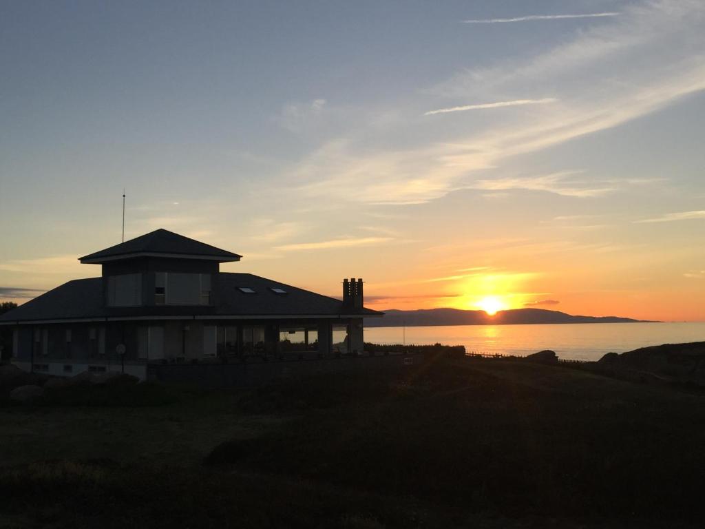 a house on the beach with the sunset in the background at Elody. Un lugar para sentirte acariciado por el mar in Ribadeo