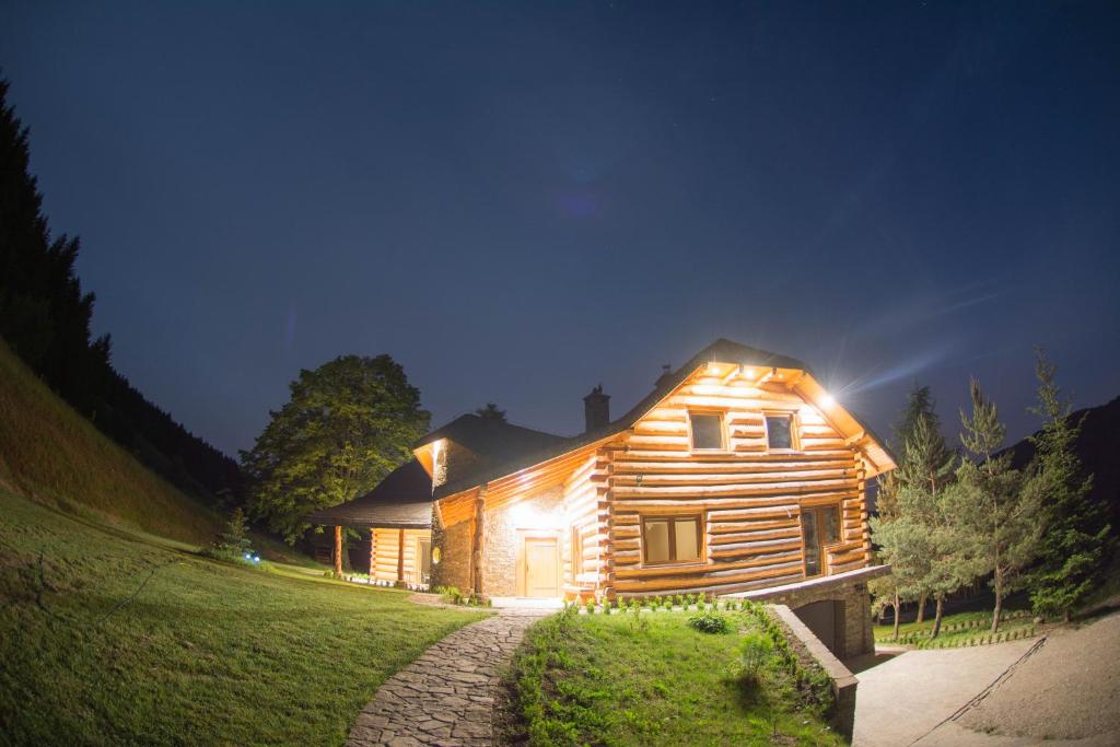 a wooden house with lights on it at night at Lipowe Wzgórze Limanowa in Limanowa