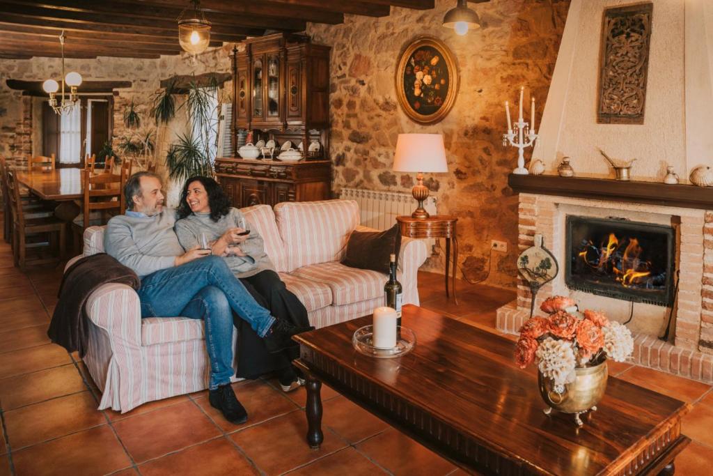 un hombre y una mujer sentados en un sofá en una sala de estar en Posada Real del Buen Camino, en Villanueva de Campeán