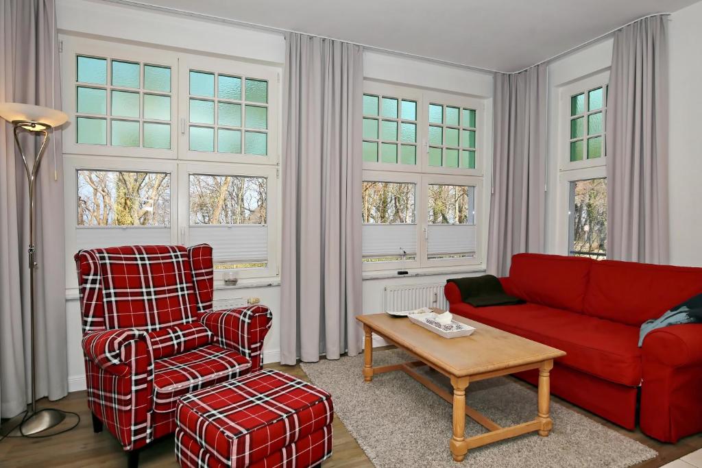 - un salon avec un canapé rouge et une chaise dans l'établissement La Mer Wohnung 1, à Kühlungsborn