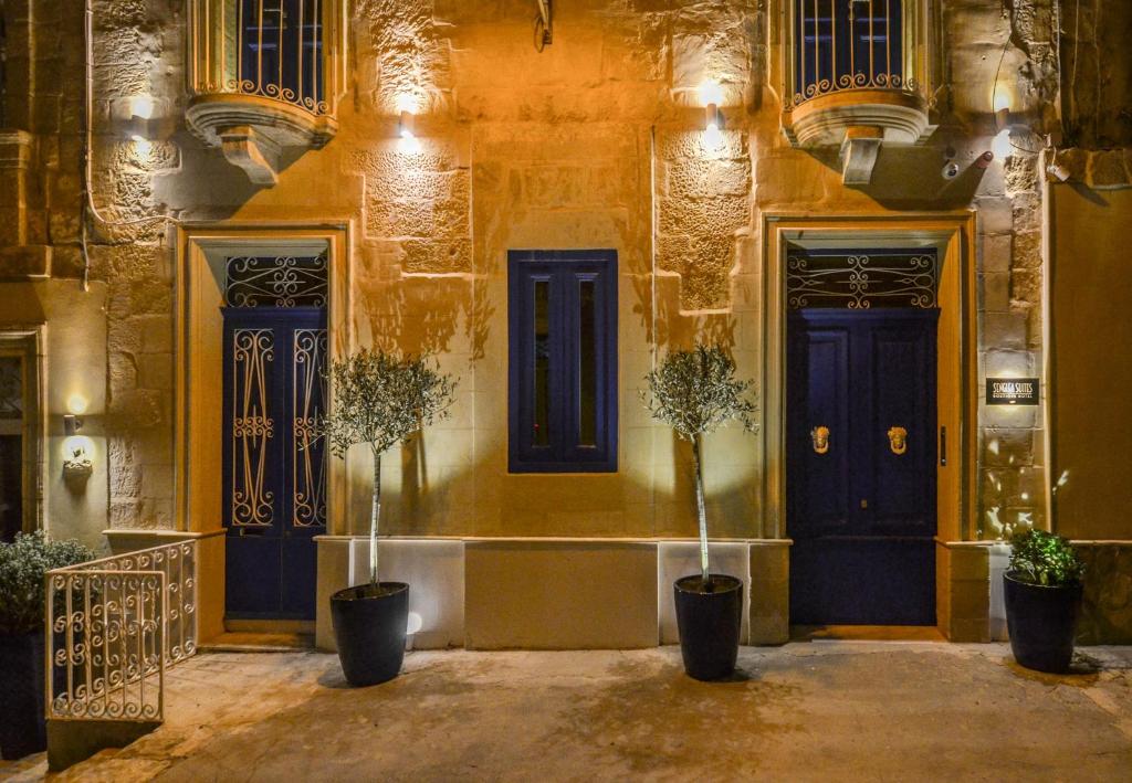 un bâtiment avec deux portes bleues et deux plantes en pot dans l'établissement Senglea Suites, à Isla