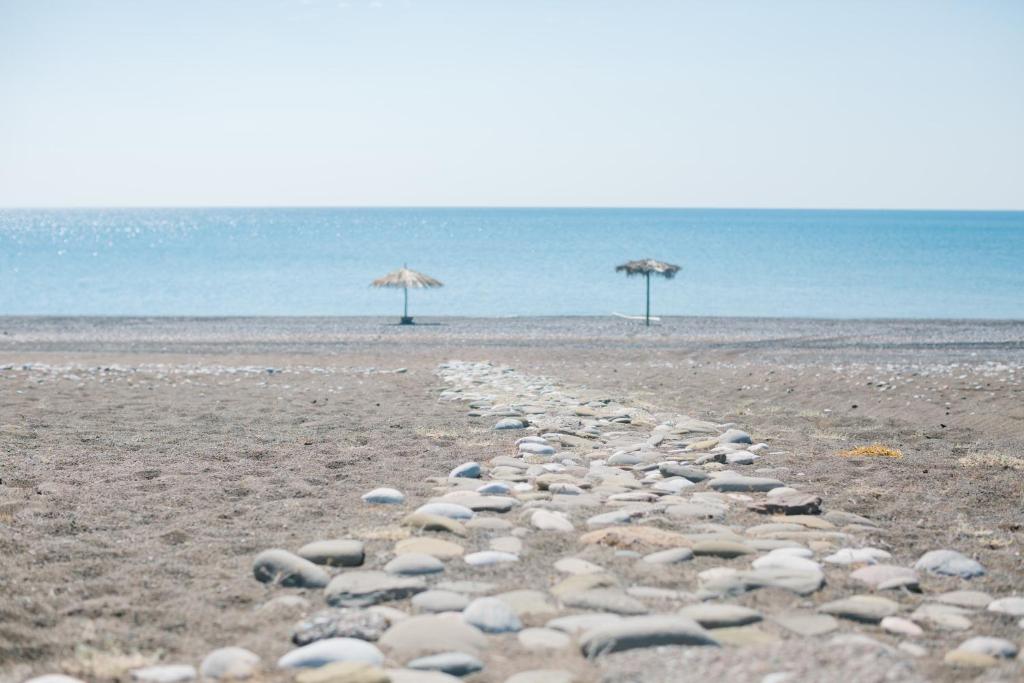 un gruppo di rocce su una spiaggia con ombrelloni di Ktima Tzaneti - Coastal Farmhouse a Lakhania