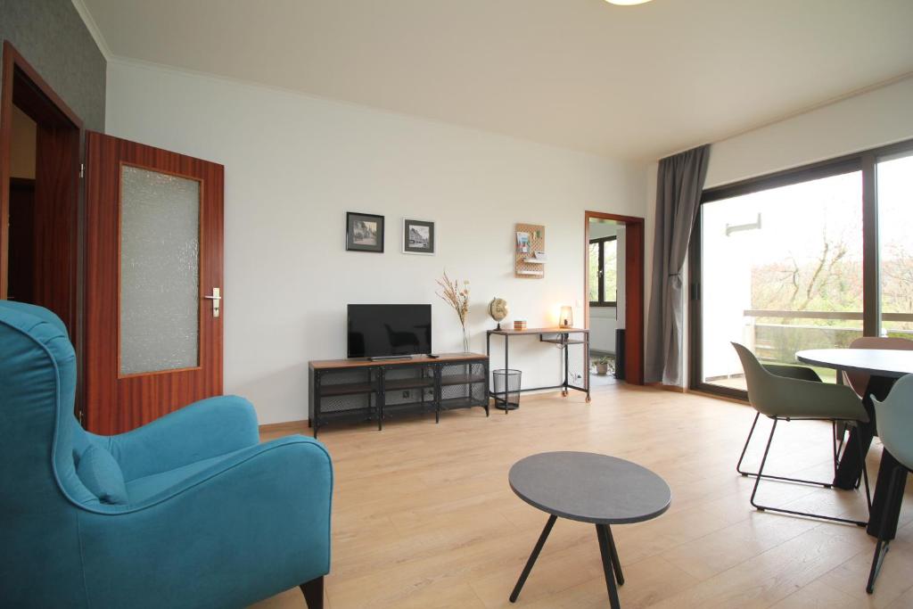 un salon avec une chaise bleue et une table dans l'établissement Oscappart, à Eupen