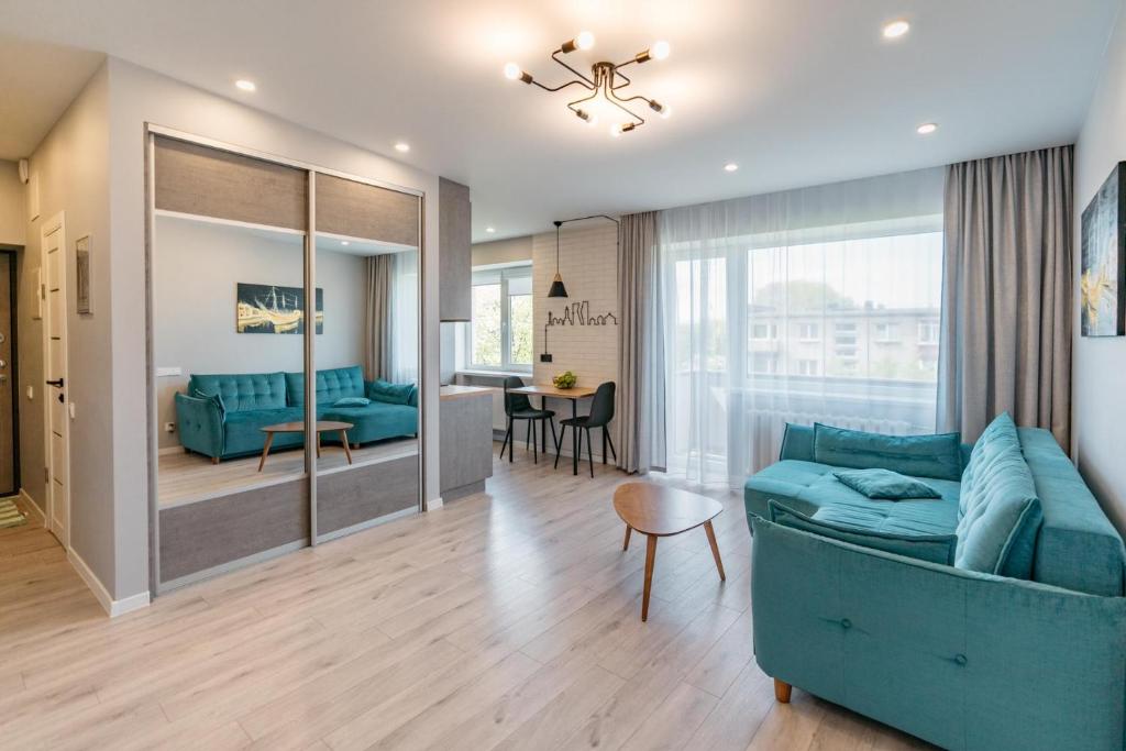 a living room with a blue couch and a table at Klaipda Gate Apartments in Klaipėda