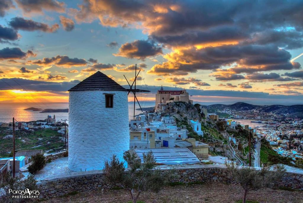 vistas a una ciudad con un molino de viento en una colina en Anemomylos-Windmill en Ermúpoli