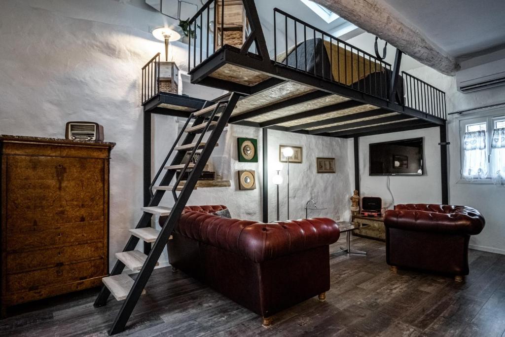 een woonkamer met een trap en een leren bank bij La Chineuse - maison de charme in LʼIsle-sur-la-Sorgue