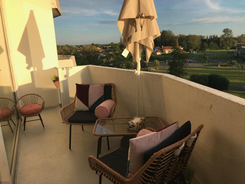 a balcony with chairs and a table and an umbrella at Studio Bee Home in De Haan