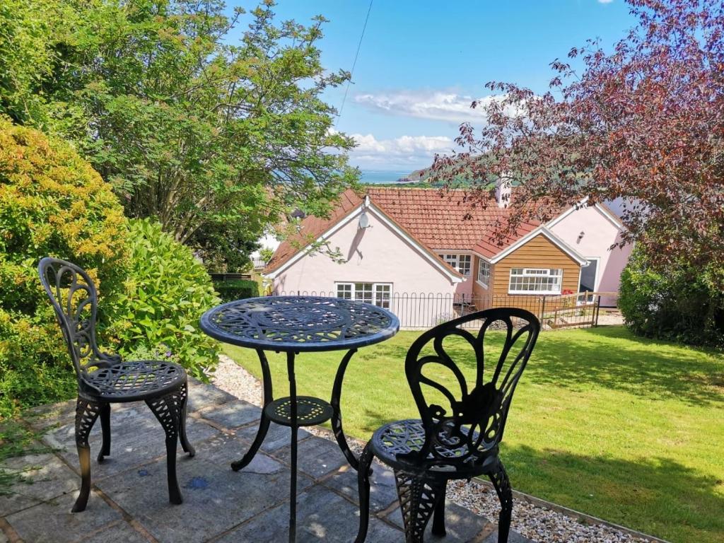 eine Terrasse mit 2 Stühlen und einem Tisch im Hof in der Unterkunft Spacious family & dog friendly home from home with sea views and private garden in Porlock