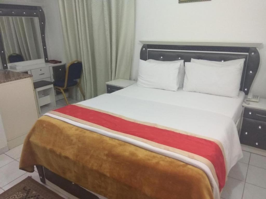 HALA HOTELS APARTMENTS في الشارقة: غرفة نوم بسرير كبير مع بطانية حمراء وبيضاء