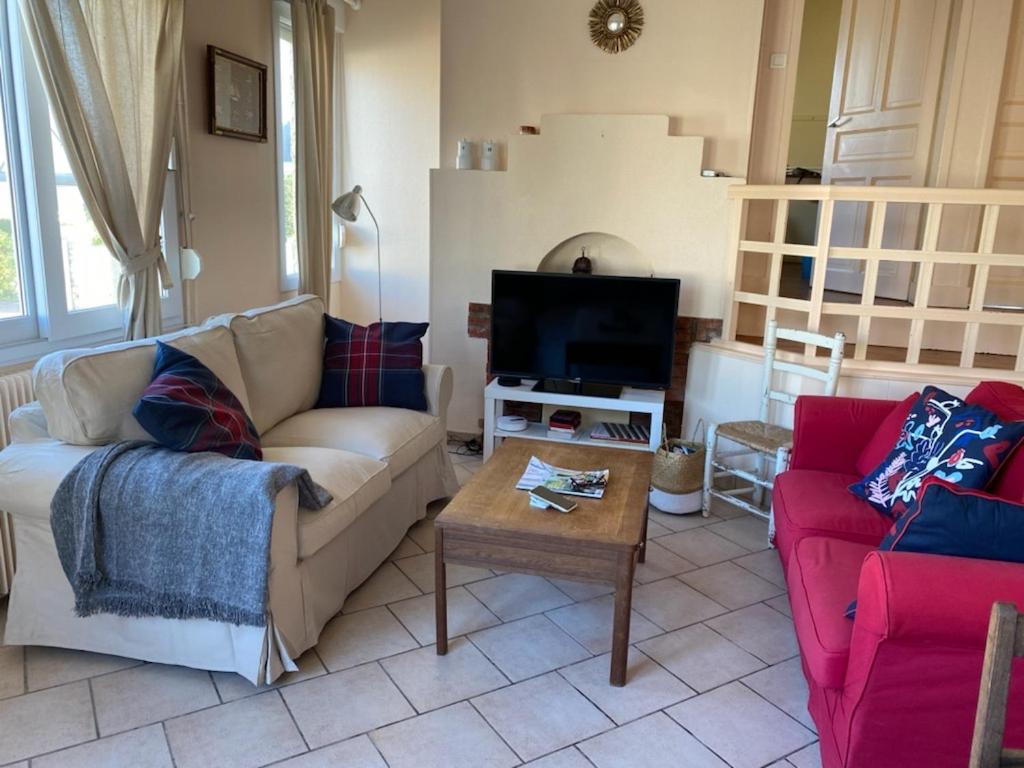 a living room with a couch and a tv at La plage au bout du jardin &#47; Sword Beach cottage in Hermanville-sur-Mer